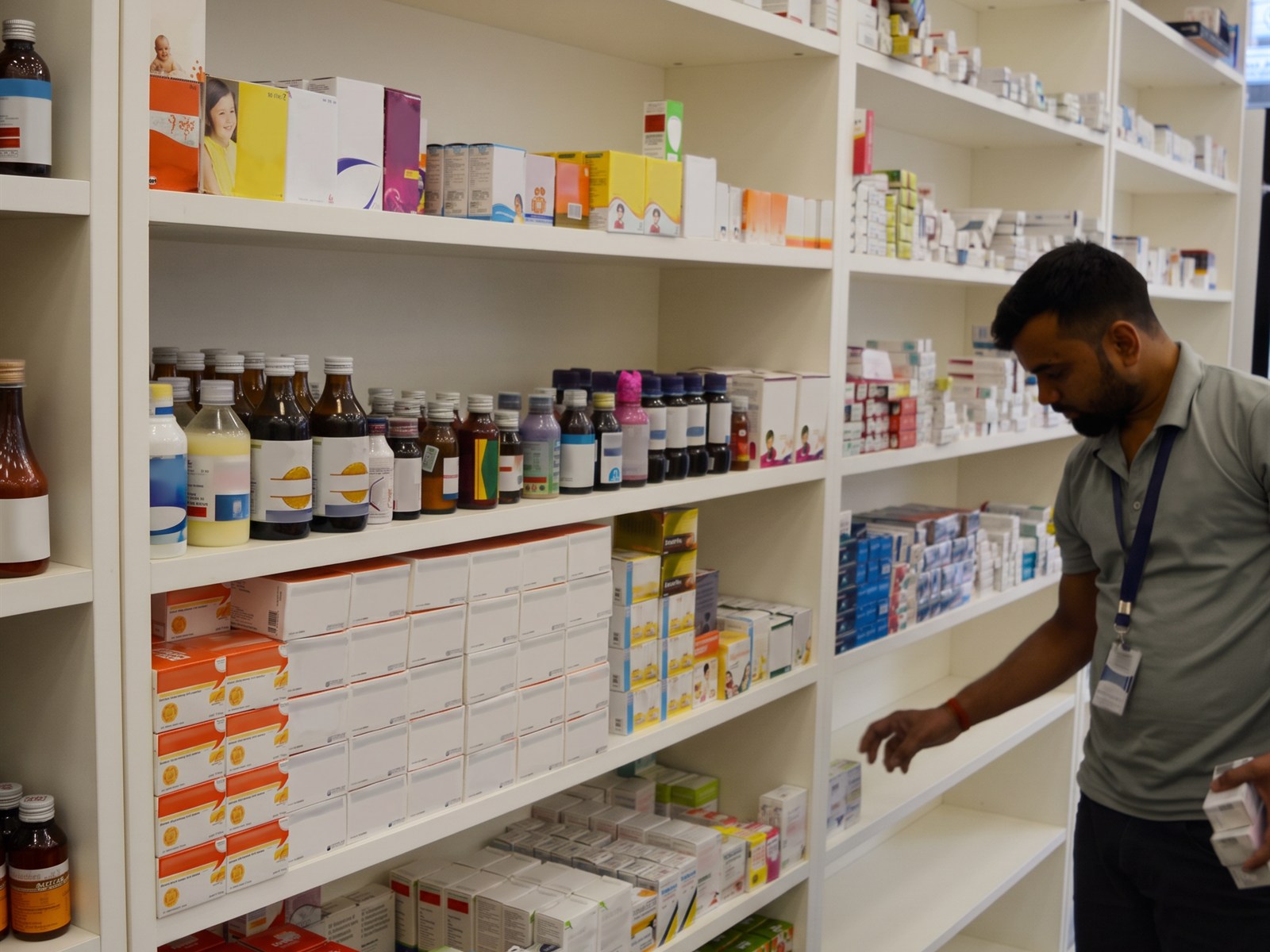 A Chemist Box team member wearing a photo ID restocking the open shelves in store